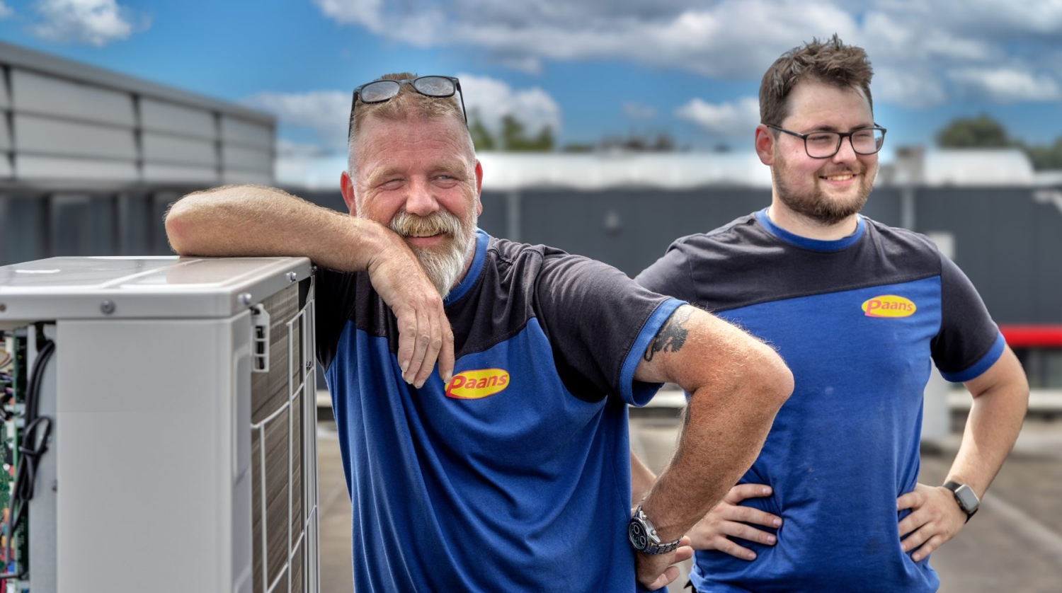 Twee monteurs van Paans bij een airco-buitenunit op het dak